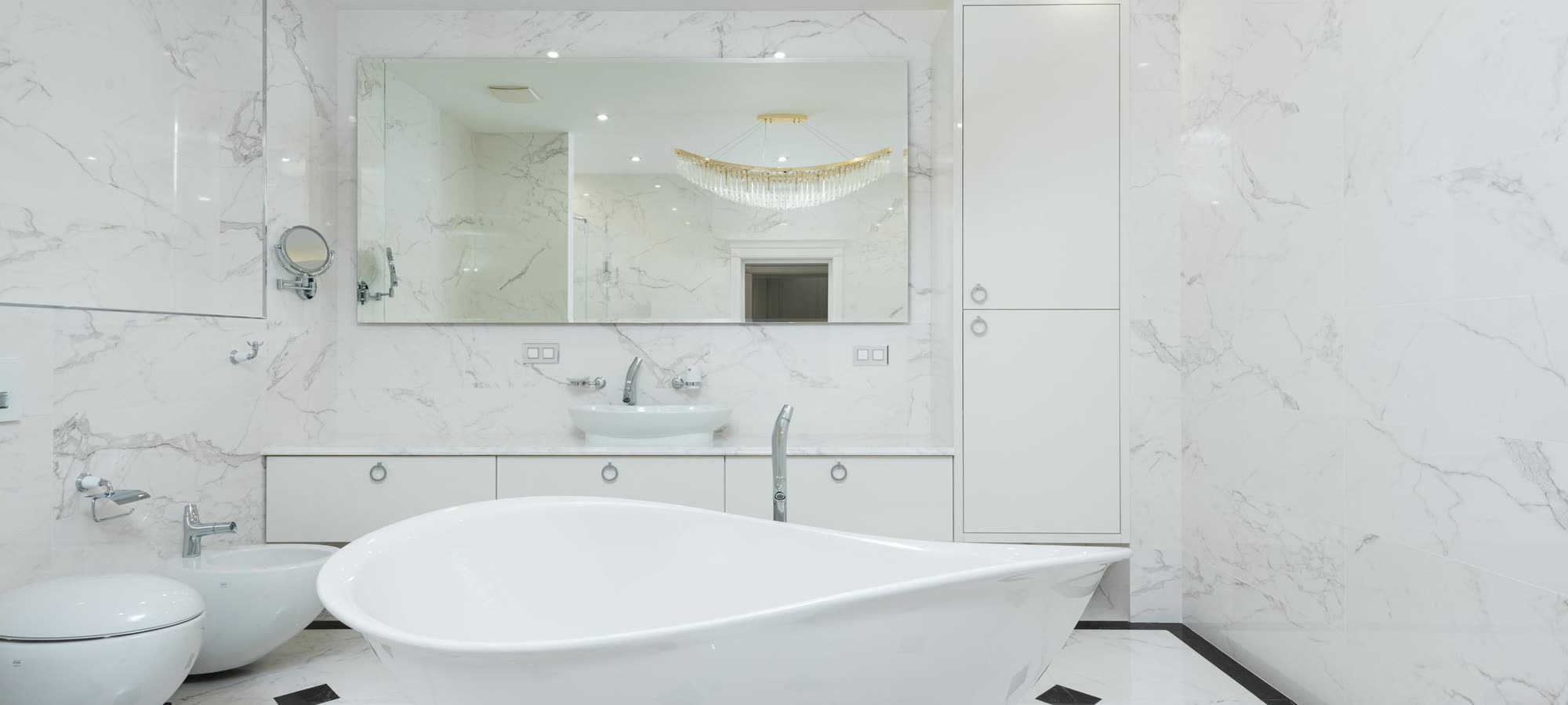 A bright white-marble bathroom with a freestanding slipper tub