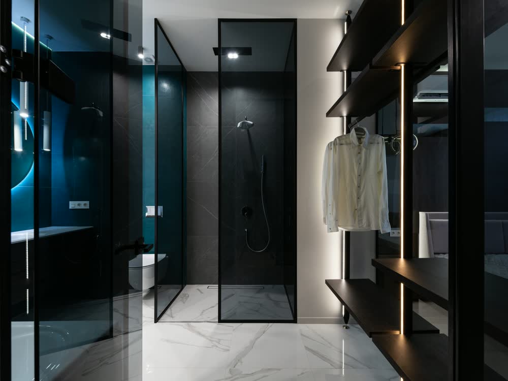 A dark-tiled bathroom with a glass shower enclosure
