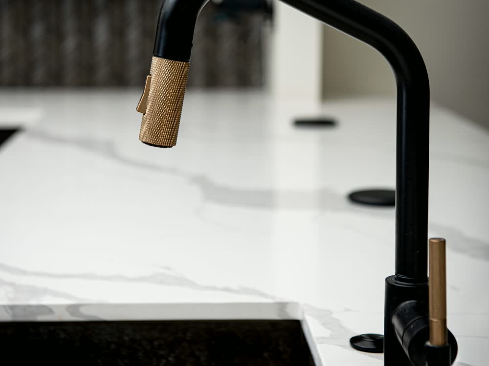 A black gooseneck kitchen tap over a marble worktop