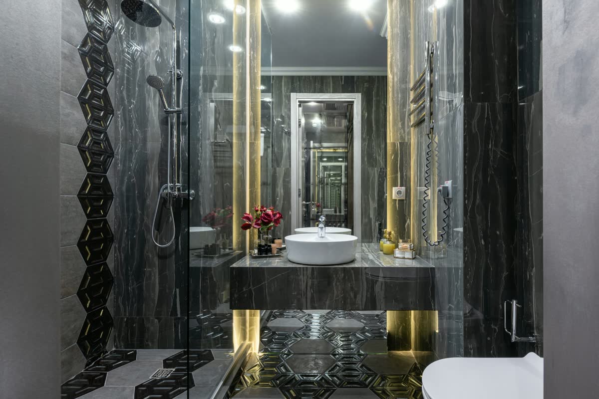 A dark marble bathroom with brass fittings